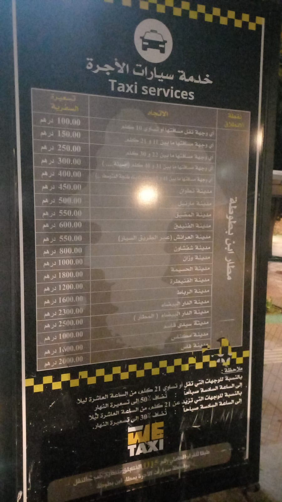 Original photograph of the Tangier Airport taxi price board, showing distance bands, named destination fares and a night surcharge notice